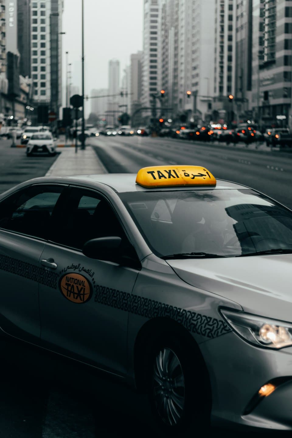 Ein silbernes Taxi fährt durch eine belebte Stadtstraße.
