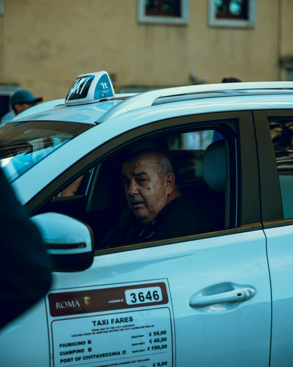 Taxifahrer blickt aus dem Fahrersitz eines weißen Taxis.