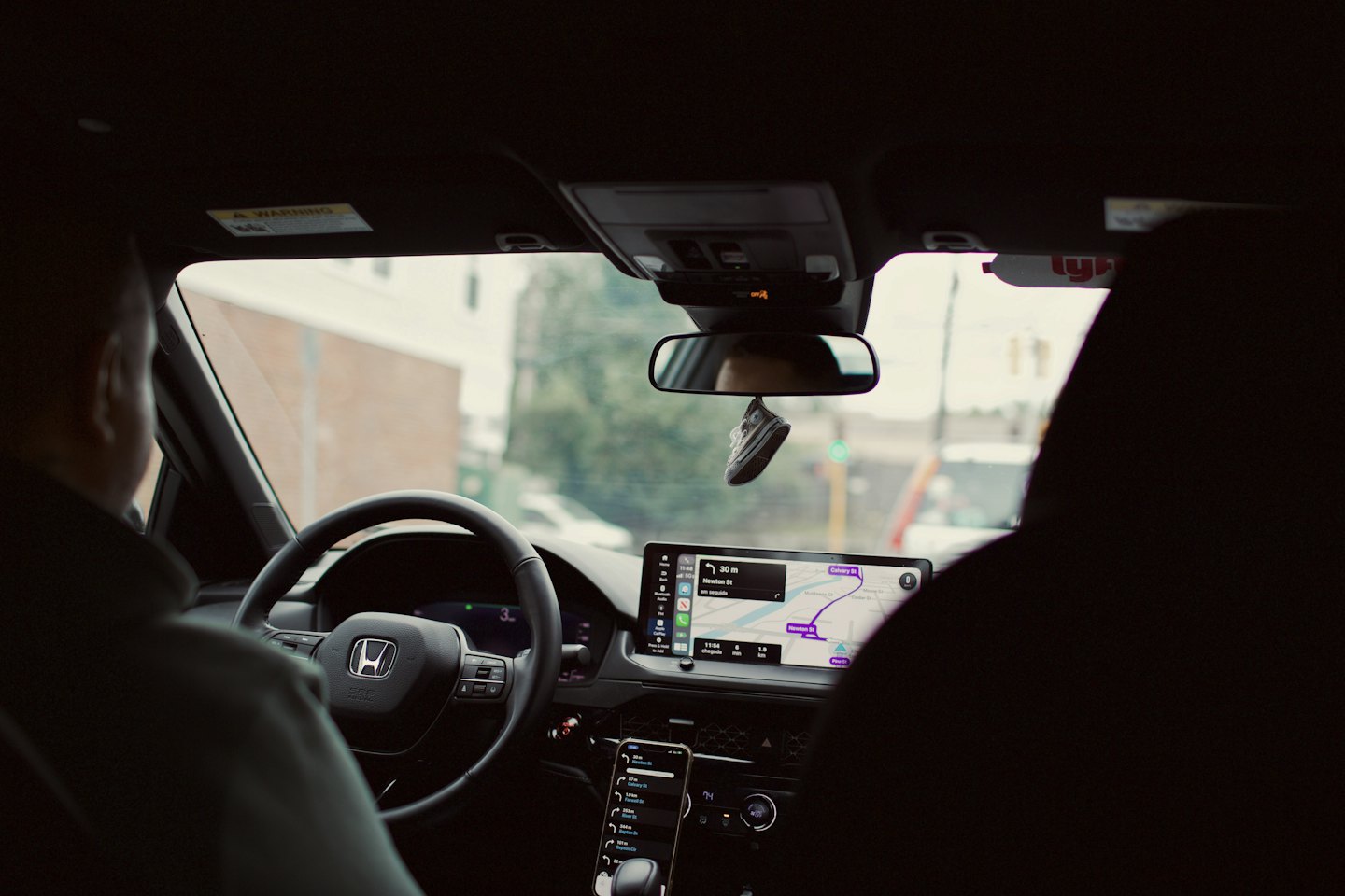 Fahrer nutzt Navigationsanzeige während der Fahrt durch Stadtstraßen.