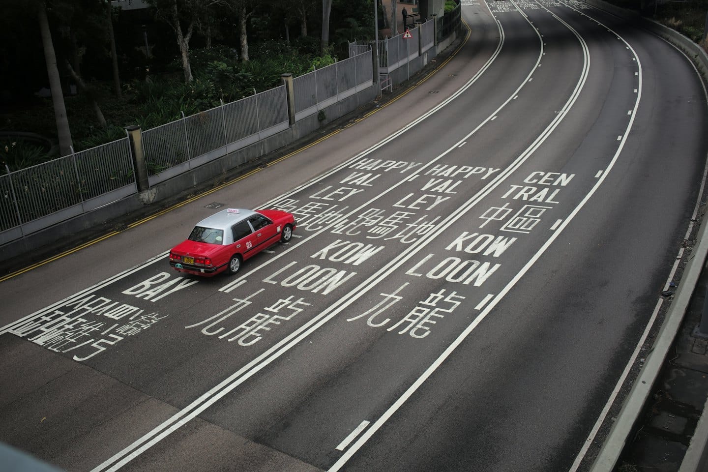 Ein roter und silberner Taxi auf nasser Stadtstraße.