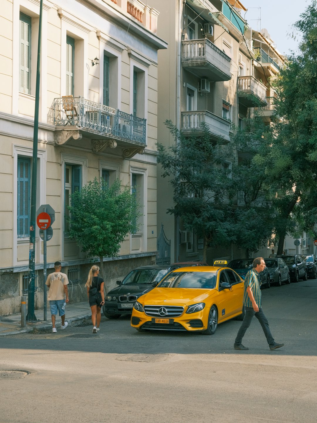 Gelber Mercedes-Benz Taxi auf einer sonnigen Stadtstraße geparkt.